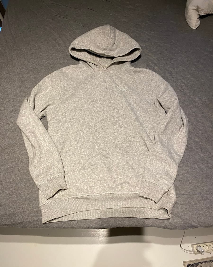 Grey hoodie photographed on a bed